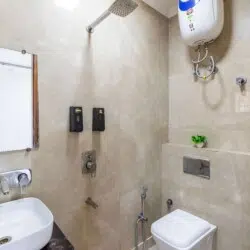 Modern attached bathroom with shower, western toilet, wash basin, and hot water facility at ValeStays serviced apartment