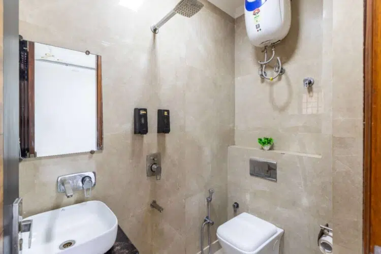 Modern attached bathroom with shower, western toilet, wash basin, and hot water facility at ValeStays serviced apartment