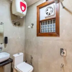 Modern attached bathroom with shower, western toilet, wash basin, and hot water facility at ValeStays serviced apartment