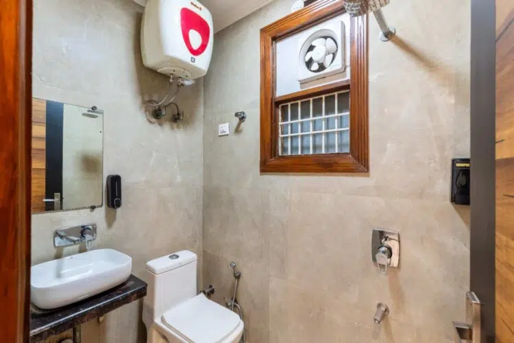 Modern attached bathroom with shower, western toilet, wash basin, and hot water facility at ValeStays serviced apartment